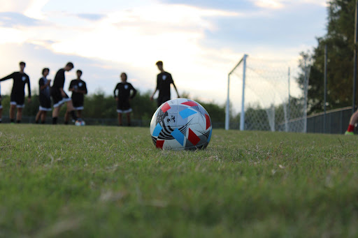 Photo taken by Blake Taylor. Players warming up in the background of a soccer ball on the CCHS practice field