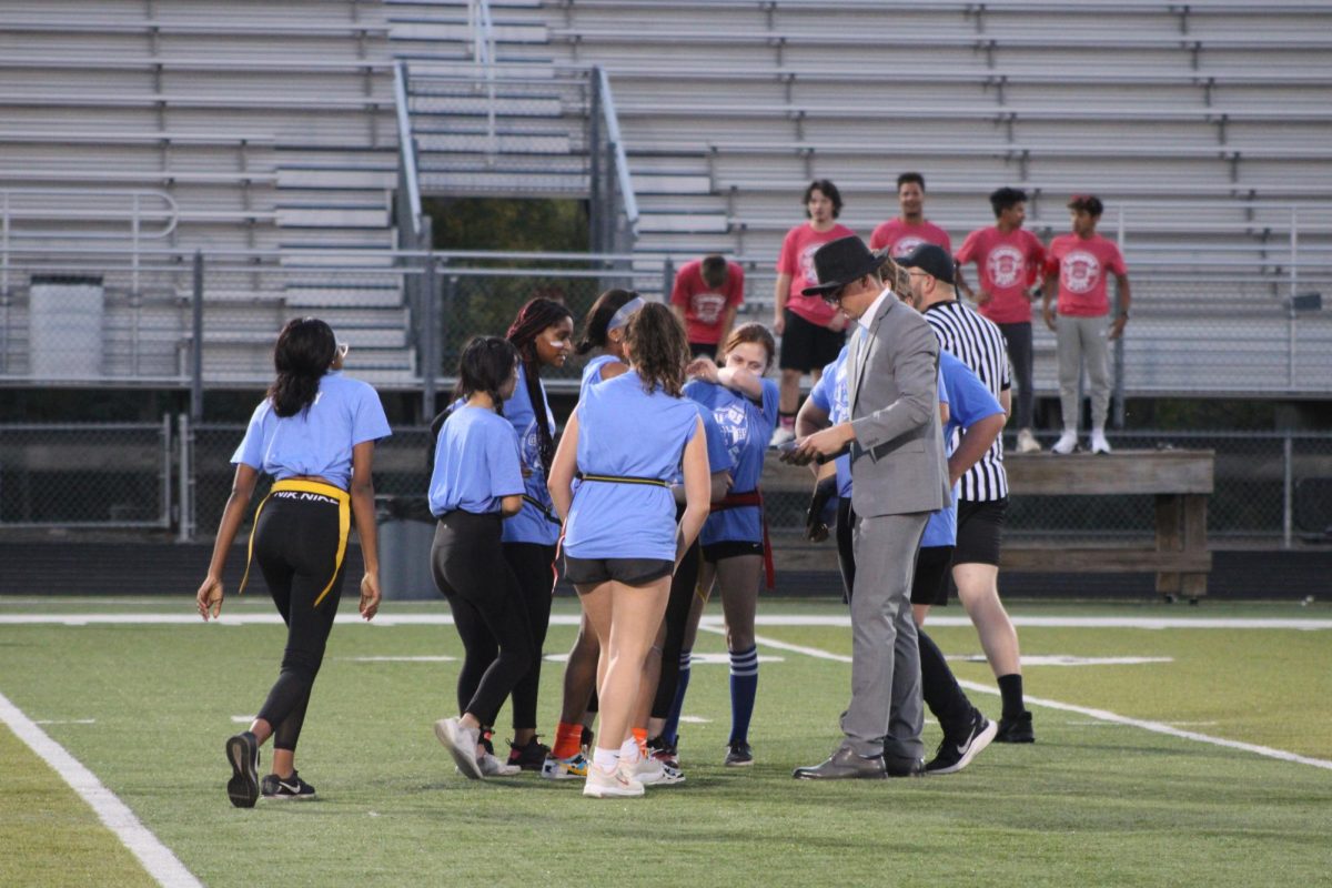 The coaches explain an upcoming play to the offensive senior team in the first half. Photo taken by Aurora Frierdich.