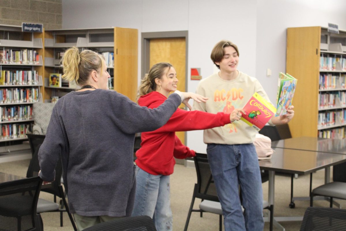Dawn Taylor, Mazzy Miller (Sophomore), and Connor Gulbrandsen (Senior) discussing a childrens book that is going to be read.